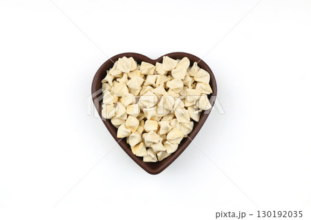 handmade manti (turkish ravioli type dumplings) on wooden heart shape bowl, before cooking. isolated on white background. 130192035