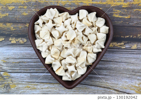 handmade manti (turkish ravioli type dumplings) on wooden heart shape bowl, before cooking 130192042