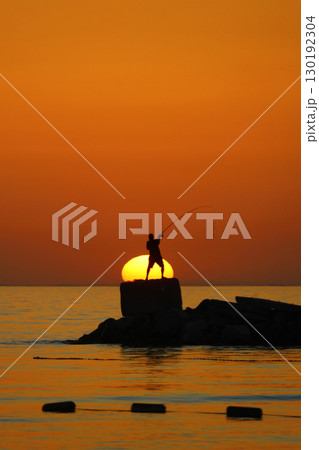Tourists on holiday in the famous resort town of Bodrum spend time fishing at sunset. 130192304