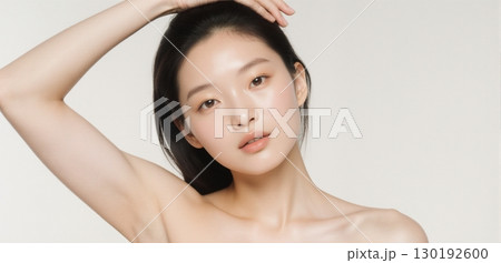 Young woman posing with arms raised showing smooth clean armpits on light background 130192600