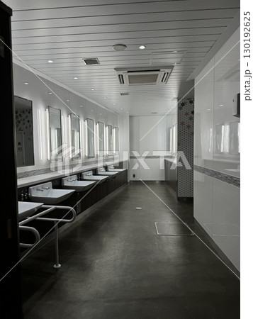 Modern bright and clean public restroom with multiple sinks, mirrors, and white interior. Concept of hygiene, cleanliness, public infrastructure and facility design. Modern bright and clean public restroom with multiple sinks, mirrors, and white interior. Concept of hygiene, cleanliness, public infrastructure and facility design. 130192625