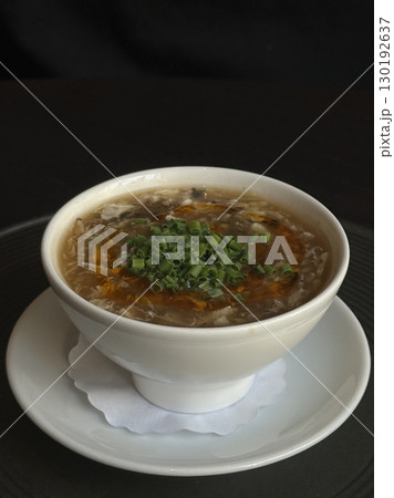 Traditional Chinese egg drop soup with mushrooms, chili oil and fresh green onions in white bowl. Concept of comfort food, Asian flavors, homemade dishes and healthy hot meals. 130192637