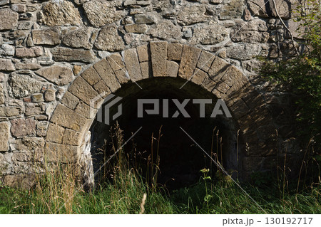 19th-century stone lime kiln in Leszczyniec, Lower Silesia, Poland, stands as an immovable heritage monument with weathered masonry, moss accents, and rustic industrial charm amid verdant surroundings 130192717