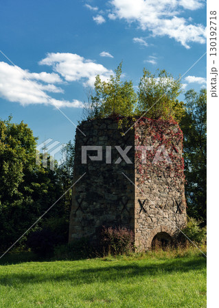 19th-century stone lime kiln in Leszczyniec, Lower Silesia, Poland, stands as an immovable heritage monument with weathered masonry, moss accents, and rustic industrial charm amid verdant surroundings 130192718