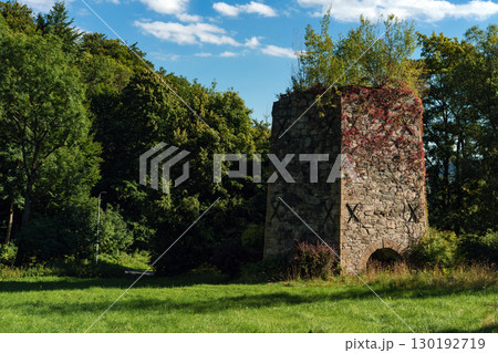 19th-century stone lime kiln in Leszczyniec, Lower Silesia, Poland, stands as an immovable heritage monument with weathered masonry, moss accents, and rustic industrial charm amid verdant surroundings 130192719