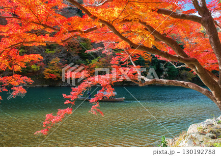 Boatman punting tourist wooden boat in autumn, Arashiyama river 130192788