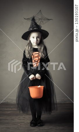 Young witch in costume holding pumpkin basket 130193107