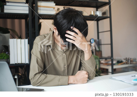 Overworked stressed businessman has headache pain while working in office. 130193333