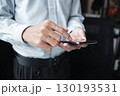 Closed-up hand of businessman using mobile phone standing near window. 130193531