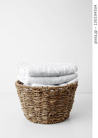 Basket filled with clean white towels in a neat arrangement. Household cleaning and hygiene concept packaging 130194504