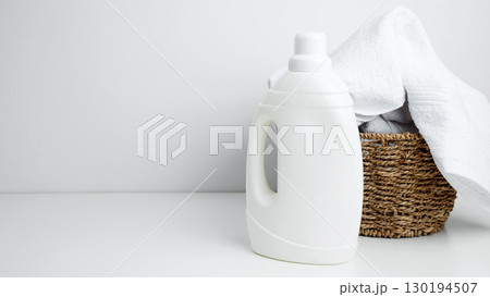 Household cleaning and hygiene concept packaging. Laundry detergent branding mock up and basket filled with clean white towels Household cleaning and hygiene concept packaging. Laundry detergent branding mock up and basket filled with clean white towels 130194507