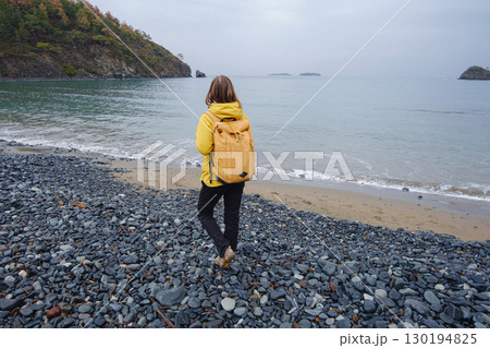 Woman walking near cloudy winter sea 130194825