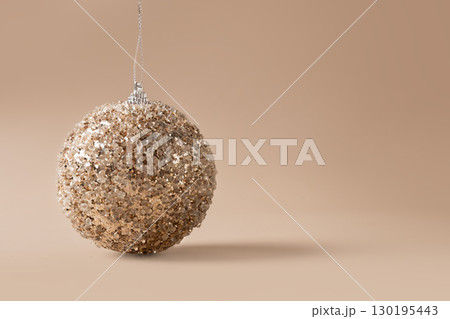 Christmas golden bauble on beige. Xmas card. Christmas golden bauble on beige. Xmas card. 130195443