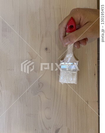 Hand Painting Wooden Surface Using a Brush with White Paint 130195455