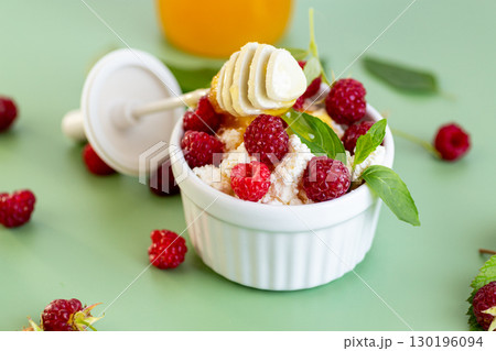 Healthy cottage cheese with raspberries and green leaves on the background Healthy cottage cheese with raspberries and green leaves on the background 130196094