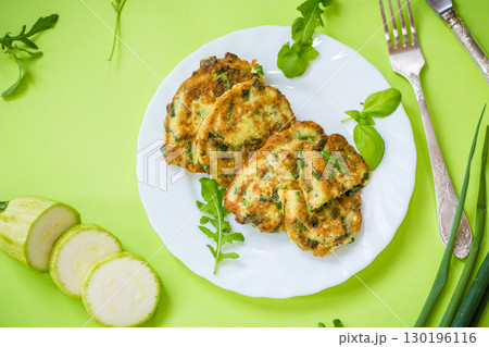 fried zucchini pancakes with green onions in a plate on a green background fried zucchini pancakes with green onions in a plate on a green background 130196116