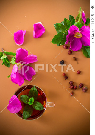 Herbal rosehip and mint tea in cup and teapot from above on brown background Herbal rosehip and mint tea in cup and teapot from above on brown background 130196140