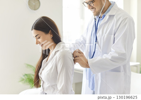 Doctor Or Nurse Using Stethoscope To Check Female Patient Lungs At Clinic 130196625