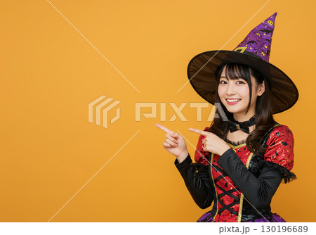 オレンジ背景に魔女の仮装をする女性 オレンジ背景に魔女の仮装をする女性 130196689