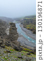 Tall rock tower by the river in a misty canyon 130196871