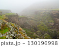 Rock formations and cracks covered with green moss in a misty landscape 130196998