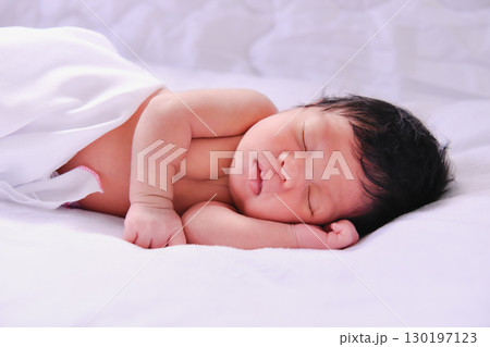 A peaceful newborn baby sleeping soundly on a soft white blanket, embodying the innocence of early life. 130197123