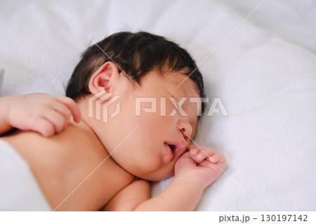 A peaceful newborn baby sleeping soundly on a soft blanket, embodying innocence and tranquility in a serene environment. A peaceful newborn baby sleeping soundly on a soft blanket, embodying innocence and tranquility in a serene environment. 130197142