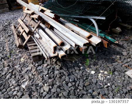Rolled Metal Sheets and Other Materials Stacked on Gravel Surface at Construction Site 130197357