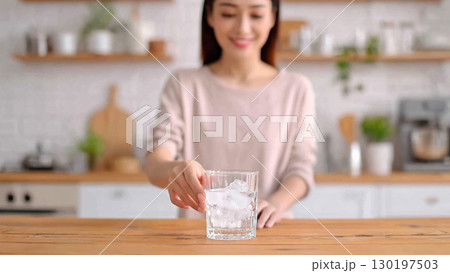 キッチンで水を飲む若い女性 130197503