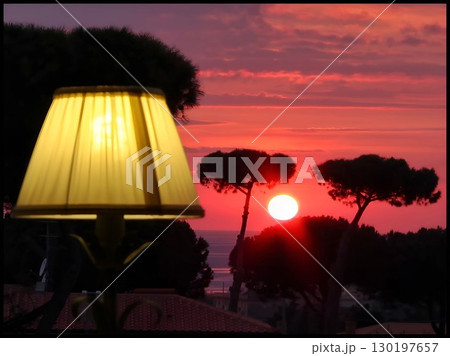 Fiery Red Sunset Over the Sea with an Illuminated Foreground Lamp 130197657