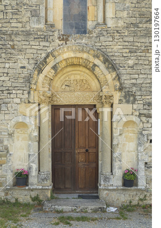Romanesque Portal of Sainte Jalle Church in Drome, France, Showing Intricate Stone Carvings and Wooden Door 130197664