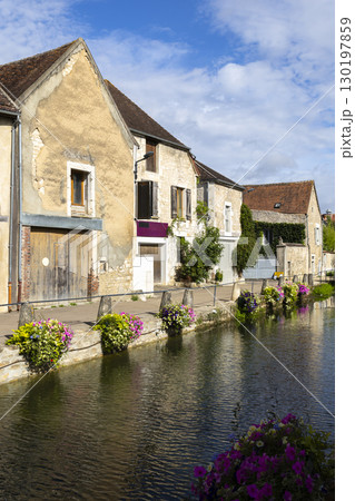 Canal flowing through Chablis village with flowers and houses reflecting in water 130197859