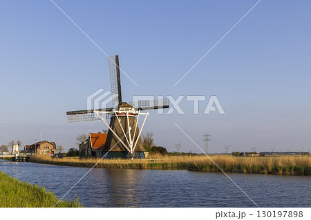 Traditional Dutch windmill standing on the banks of a canal in North Holland, Netherlands Traditional Dutch windmill standing on the banks of a canal in North Holland, Netherlands 130197898