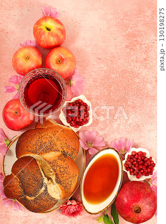 Jewish holiday Rosh Hashanah concept with apples, honey, pomegranate, flowers, red wine and festive challah bread for greeting card, creative mockup and template for Jewish New Year. 130198275