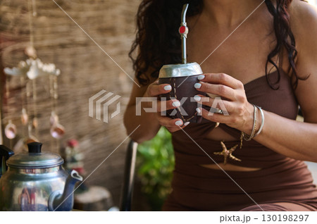 Woman Enjoying a Traditional Yerba Mate Drink in a Cozy Outdoor Setting 130198297