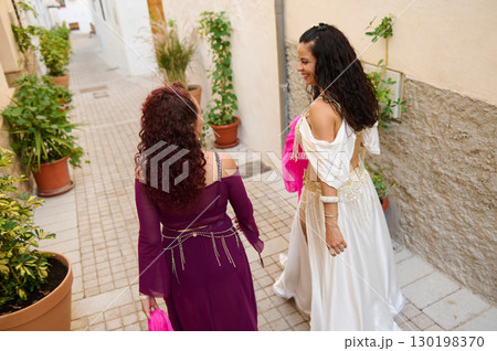 Two Women Enjoying a Charming Alleyway in Colorful Dresses and Smiles 130198370