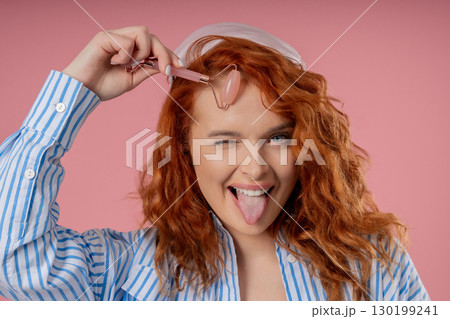 Charming Woman Doing Face Massage With Rose Quartz Stone Roller For Firmer Charming Woman Doing Face Massage With Rose Quartz Stone Roller For Firmer 130199241