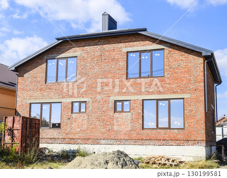 Two-storey house made of red brick. Metal-plastic windows. Newly built house. Two-storey house made of red brick. Metal-plastic windows. Newly built house. 130199581