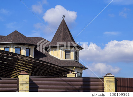 Decorative metal on the roof of a brick house. Fence made of corrugated metal. Decorative metal on the roof of a brick house. Fence made of corrugated metal. 130199591