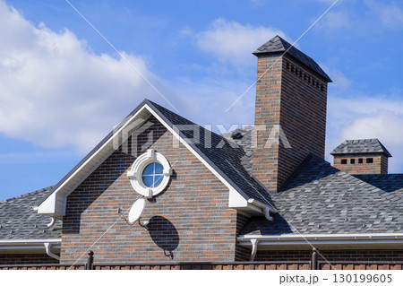 Asphalt shingle. Decorative bitumen shingles on the roof of a brick house. Asphalt shingle. Decorative bitumen shingles on the roof of a brick house. 130199605