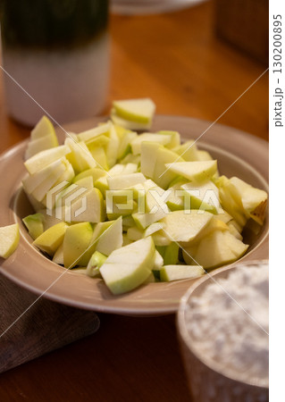Freshly chopped green apples in a beige plate on a wooden table, prepared for baking Freshly chopped green apples in a beige plate on a wooden table, prepared for baking 130200895