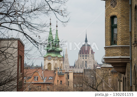 View of the green copper towers of St. Anne Church and the iconic dome of the Hungarian Parliament Building in Budapest View of the green copper towers of St. Anne Church and the iconic dome of the Hungarian Parliament Building in Budapest 130201155