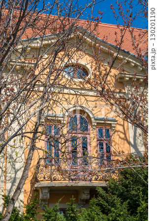 Elegant peach-colored villa in Budapest with ornate pink window frames and wrought iron balcony 130201190