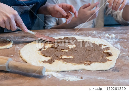 Family making cinnamon rolls together Family making cinnamon rolls together 130201220