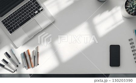 A white desk showcasing a laptop, coffee cup, plant, and essential office supplies for an organized environment 130203390