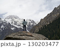 asian man standing on top of rock looking at peak of snow mountain 130203477