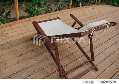 Comfortable lounge chairs with white cushions located in a forest recreation area for enjoying beauty and fresh air 130203576