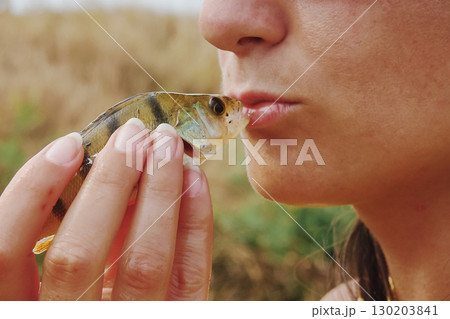 A girl kisses a small sunfish before it makes a wish come true 130203841