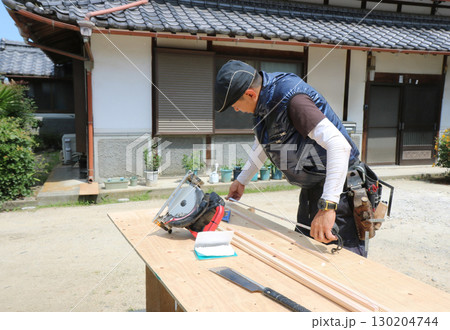 大工さんが作業台でコンベックスで木材を計測している 大工さんが作業台でコンベックスで木材を計測している 130204744