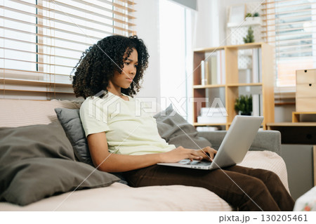 Young woman using a tablet in a cozy home, capturing creativity, relaxation, and digital connection Young woman using a tablet in a cozy home, capturing creativity, relaxation, and digital connection 130205461